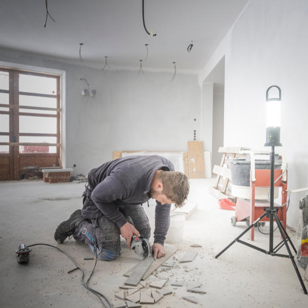 Ledlenser AL10R Work Lantern on a tripod stand lighting an indoor construction site with a worker cutting wood