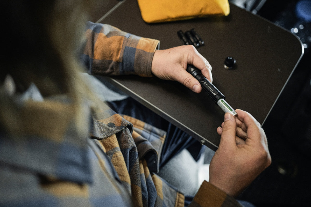 Ledlenser P5R Torch held in hand battery being inserted on a worktable