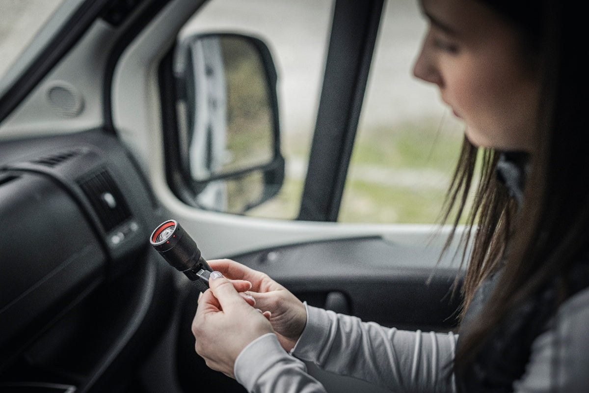 Ledlenser P6R Torch held by a person inside a vehicle cab black body with red bezel shown for handheld use