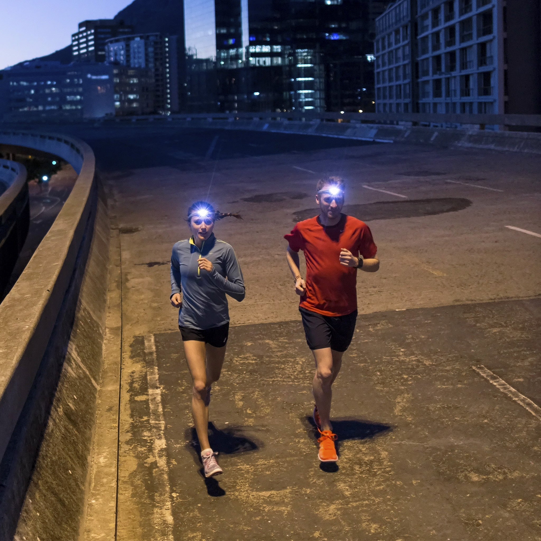 NEO Blue Battery Operated Headlamp worn by a runner on a night street; two runners with headlamps in urban environment
