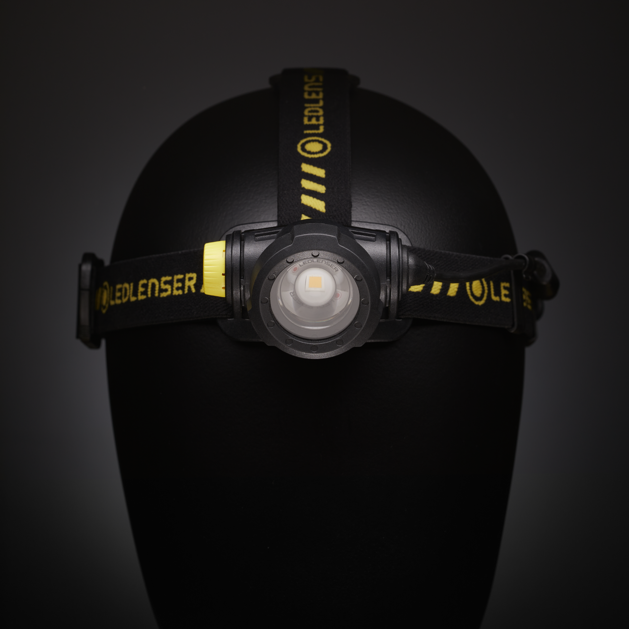 H7R Work Headlamp mounted on a headband on a mannequin head; black strap with yellow Ledlenser branding front LED module visible