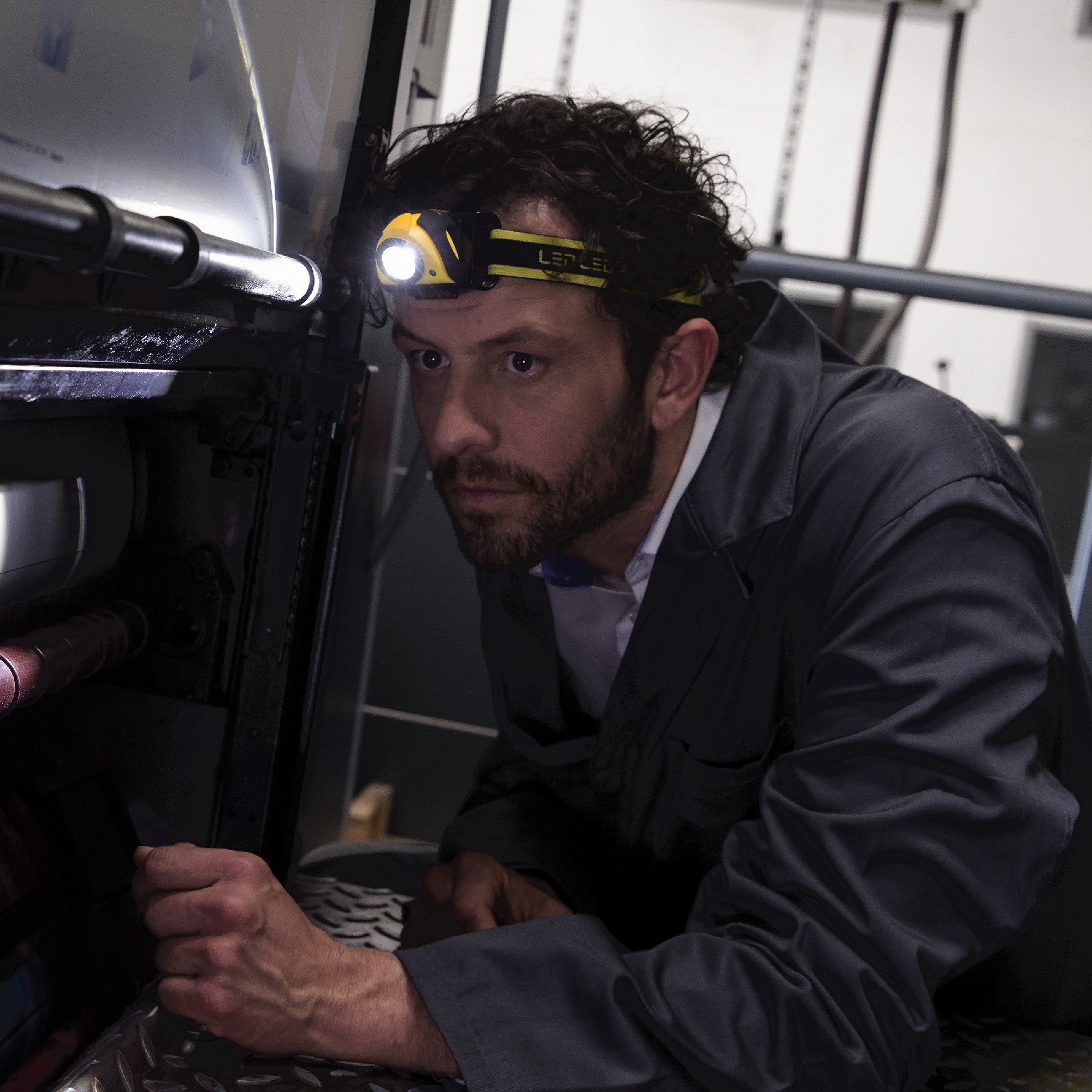 iSEO3 Battery Operated Headlamp worn by a man inspecting industrial equipment in a dim workshop