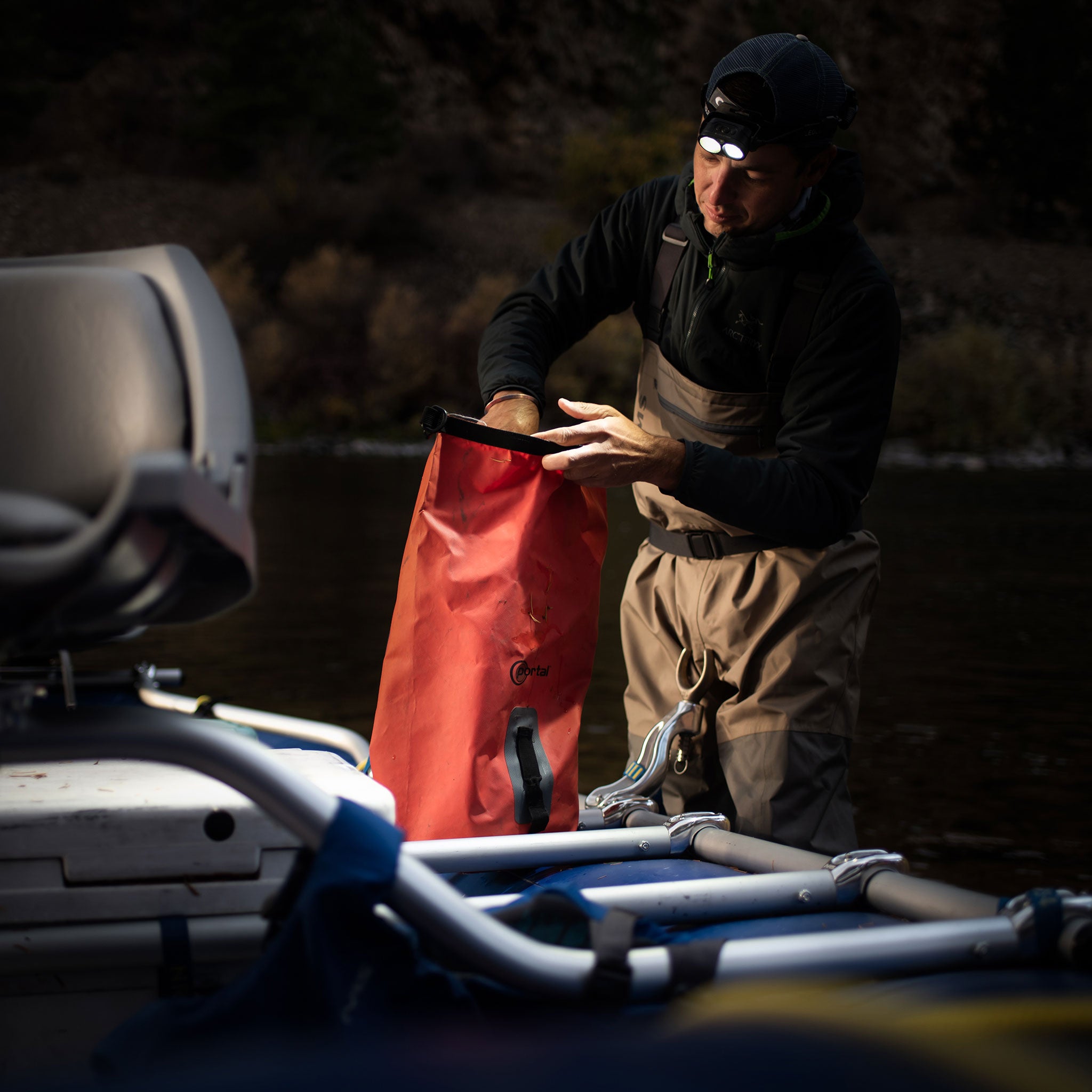 Ledlenser H19R Core Headlamp worn by a man on a boat at dusk handling an orange dry bag near gear