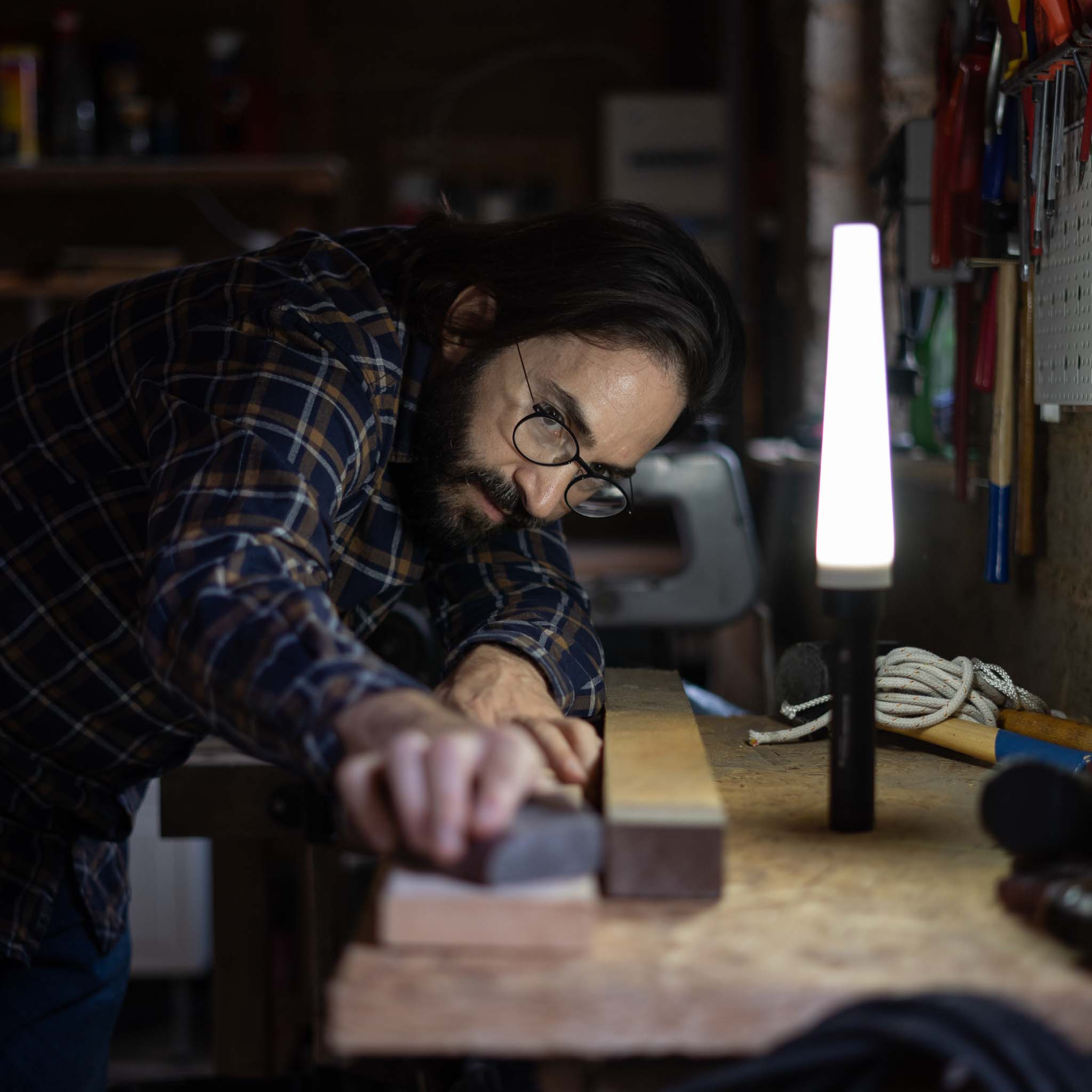 Ledlenser Signal Cone W 42mm Suits P6R Work & P7R Work Torches on a workshop bench beside a vertical LED lamp with a man in plaid shirt sanding wood
