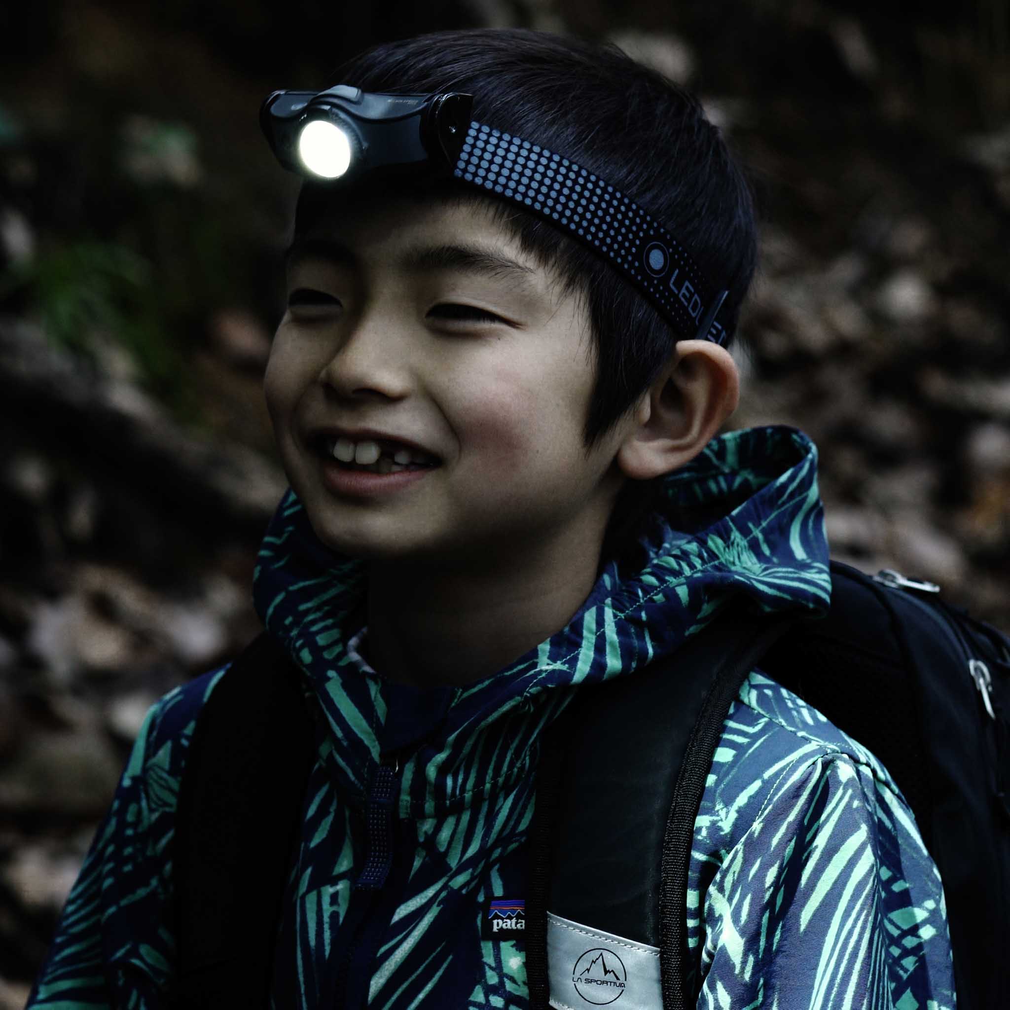 Ledlenser MH5 Powercase Combo headlamp worn on a young person’s head with a bright front light