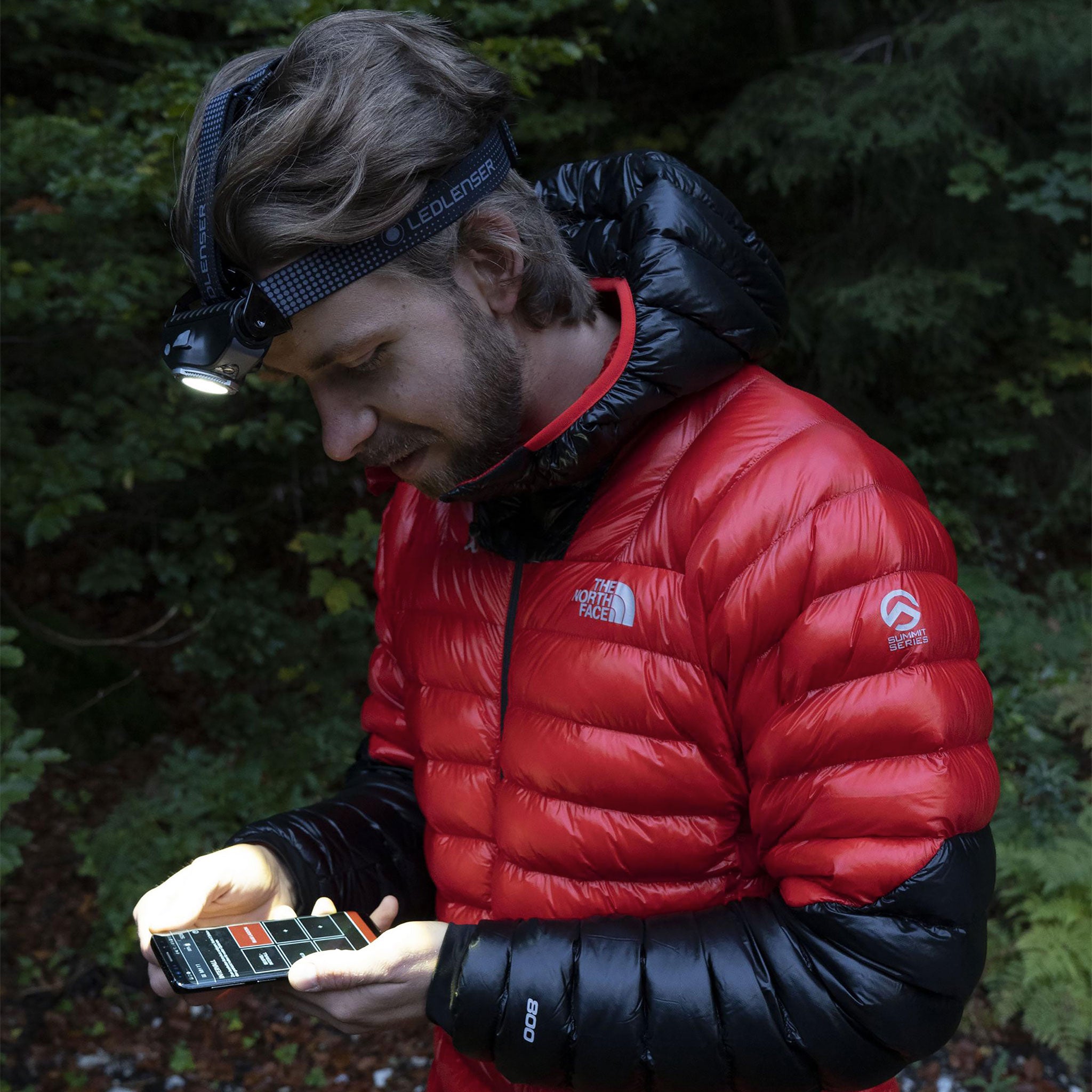 MH11 Outdoor Headlamp worn on a headband by a man outdoors in a red jacket headlamp front light visible