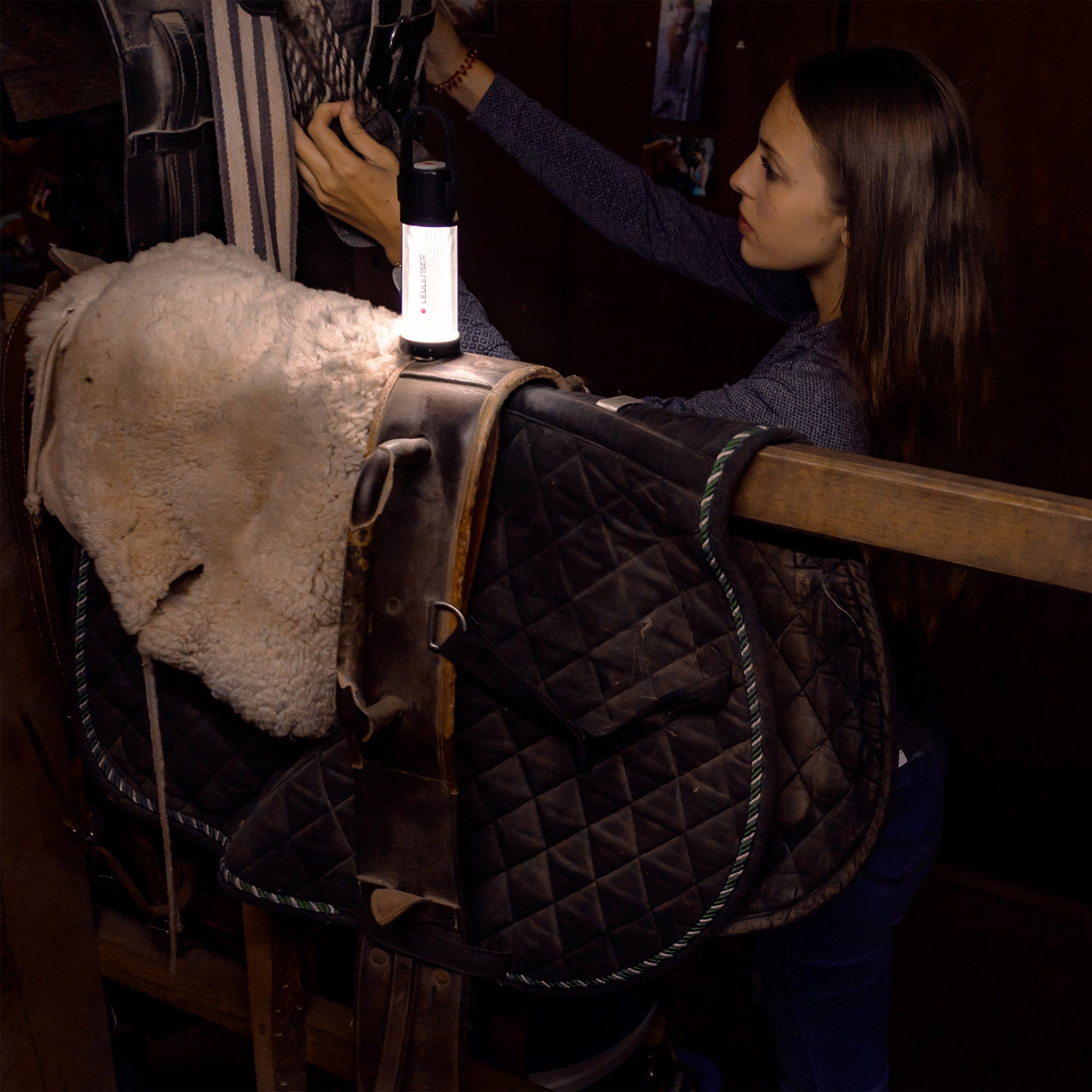 ML6 Lantern mounted on a horse saddle in a dim stable with a person guiding the light on the saddle