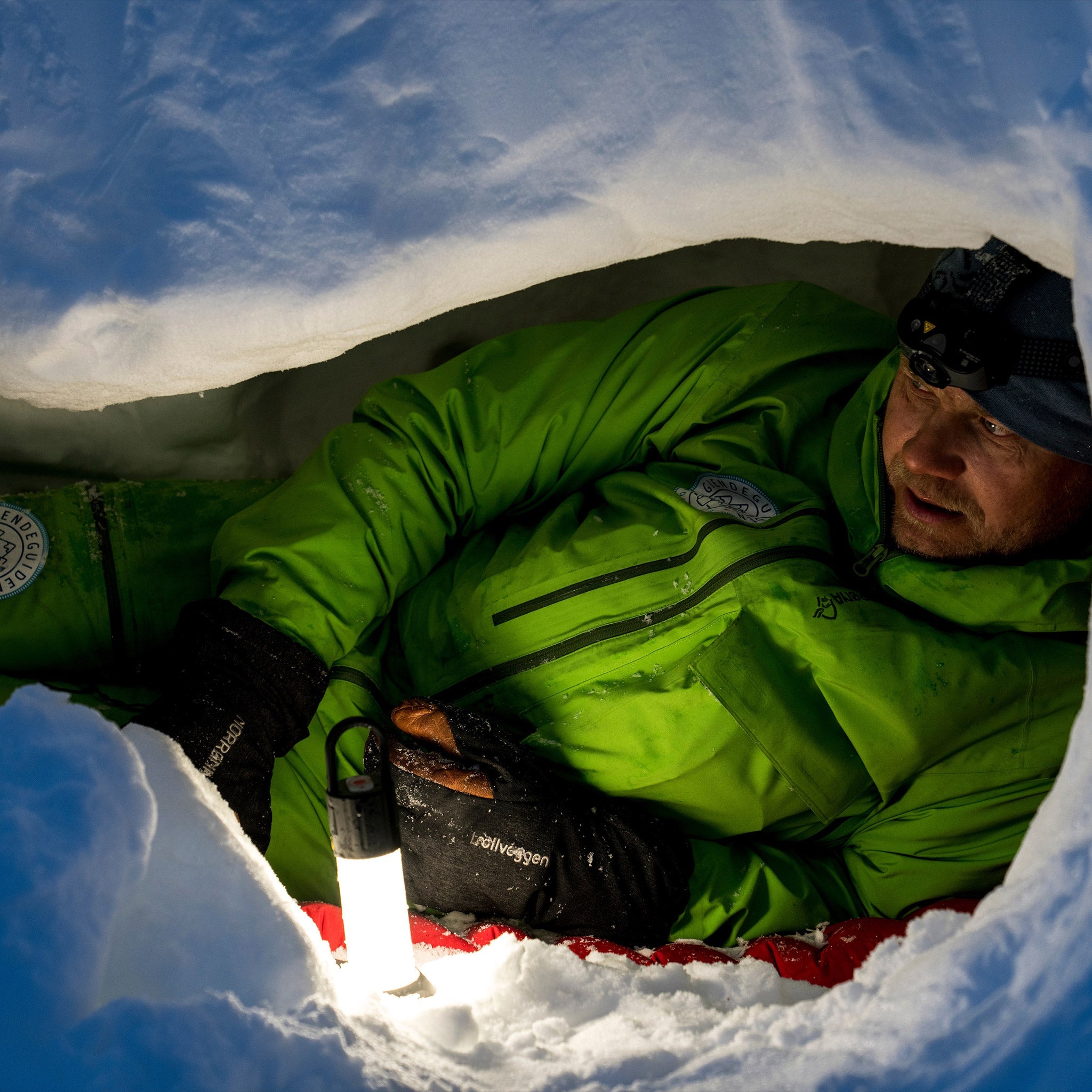ML6 Lantern visible with glow held by a person in a bright green jacket inside a snow cave