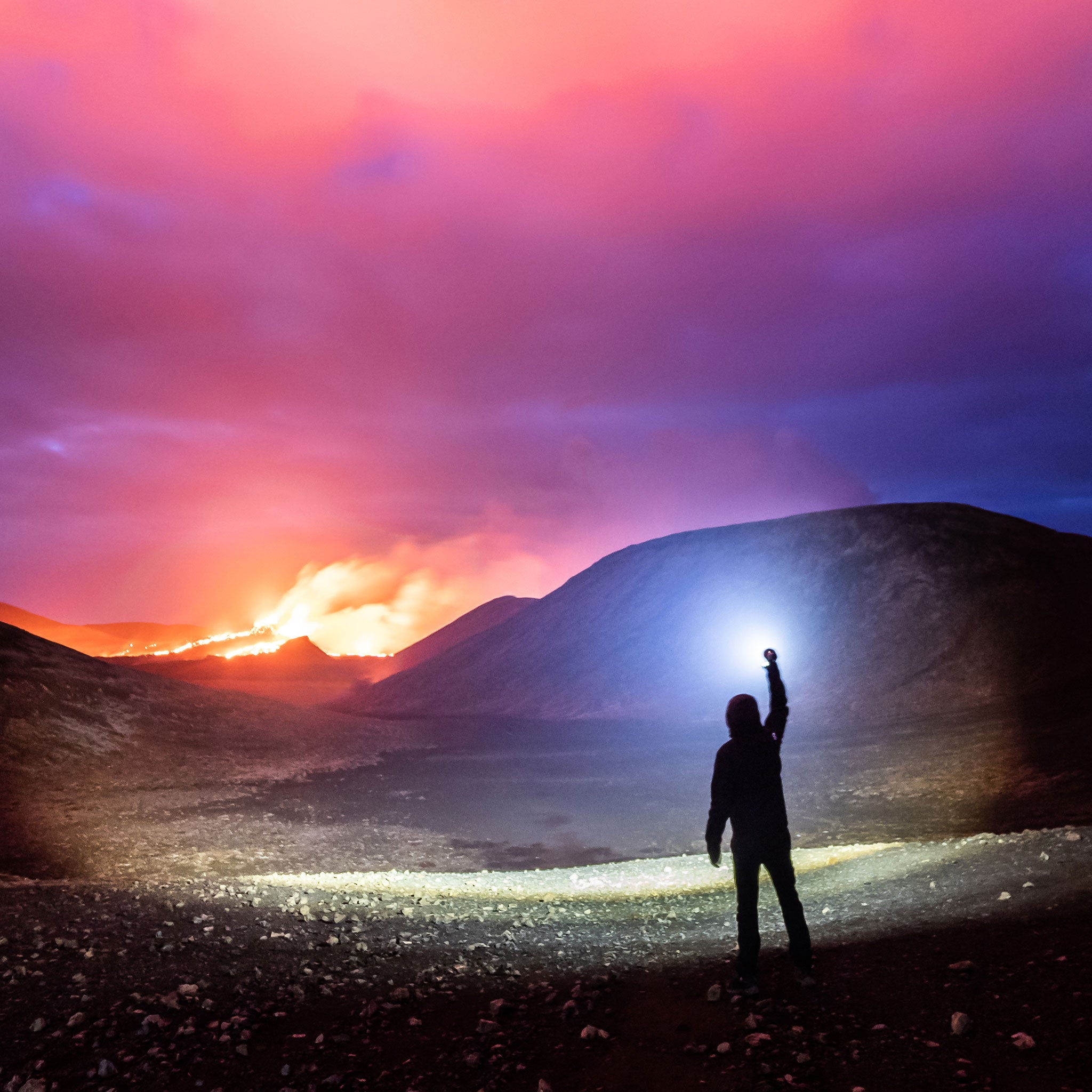 P18R Signature Torch held aloft by a silhouetted person in a volcanic landscape under a colorful sky with a blue beam