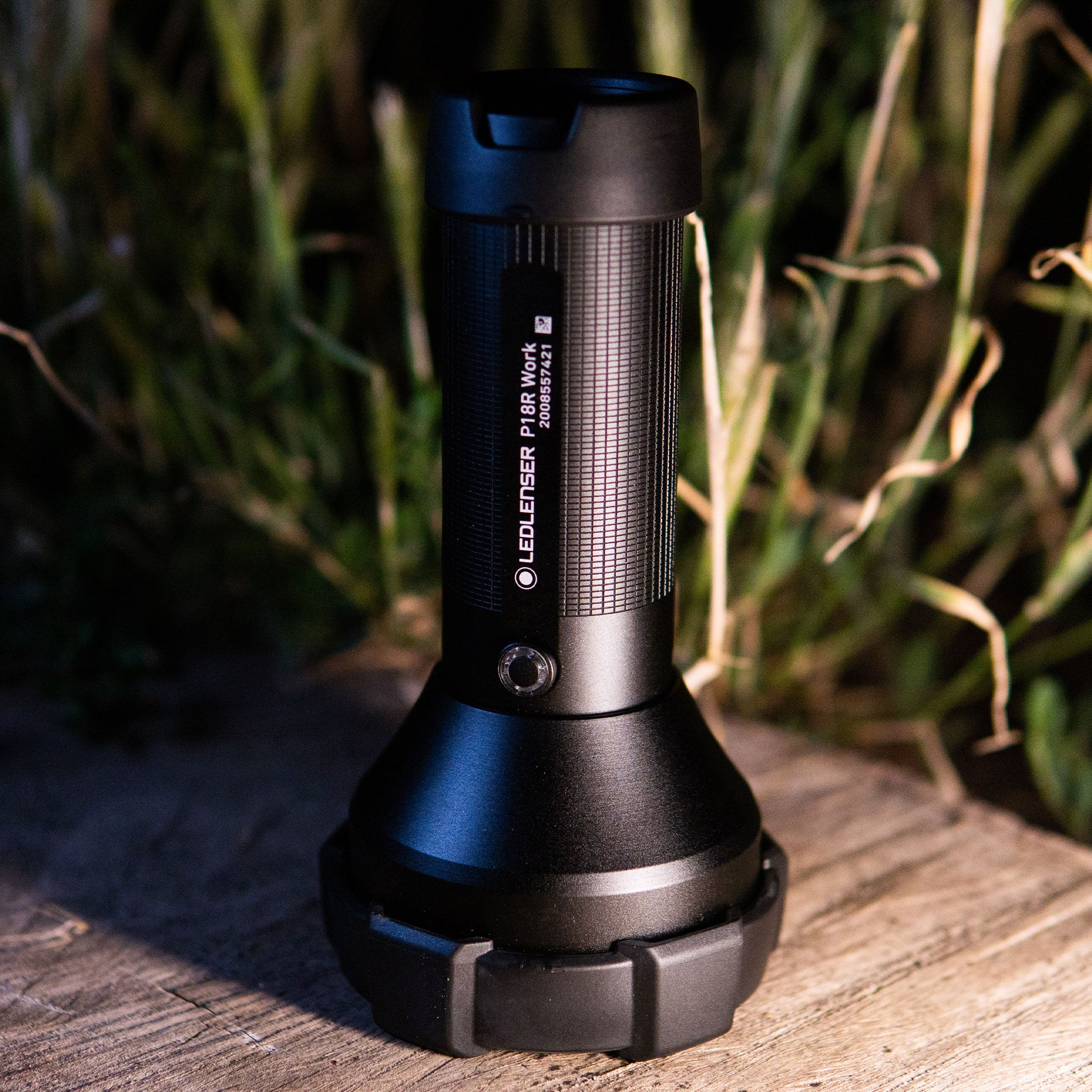 Ledlenser P18R Work Torch upright on a wooden surface with a textured black body and protective cap at the top