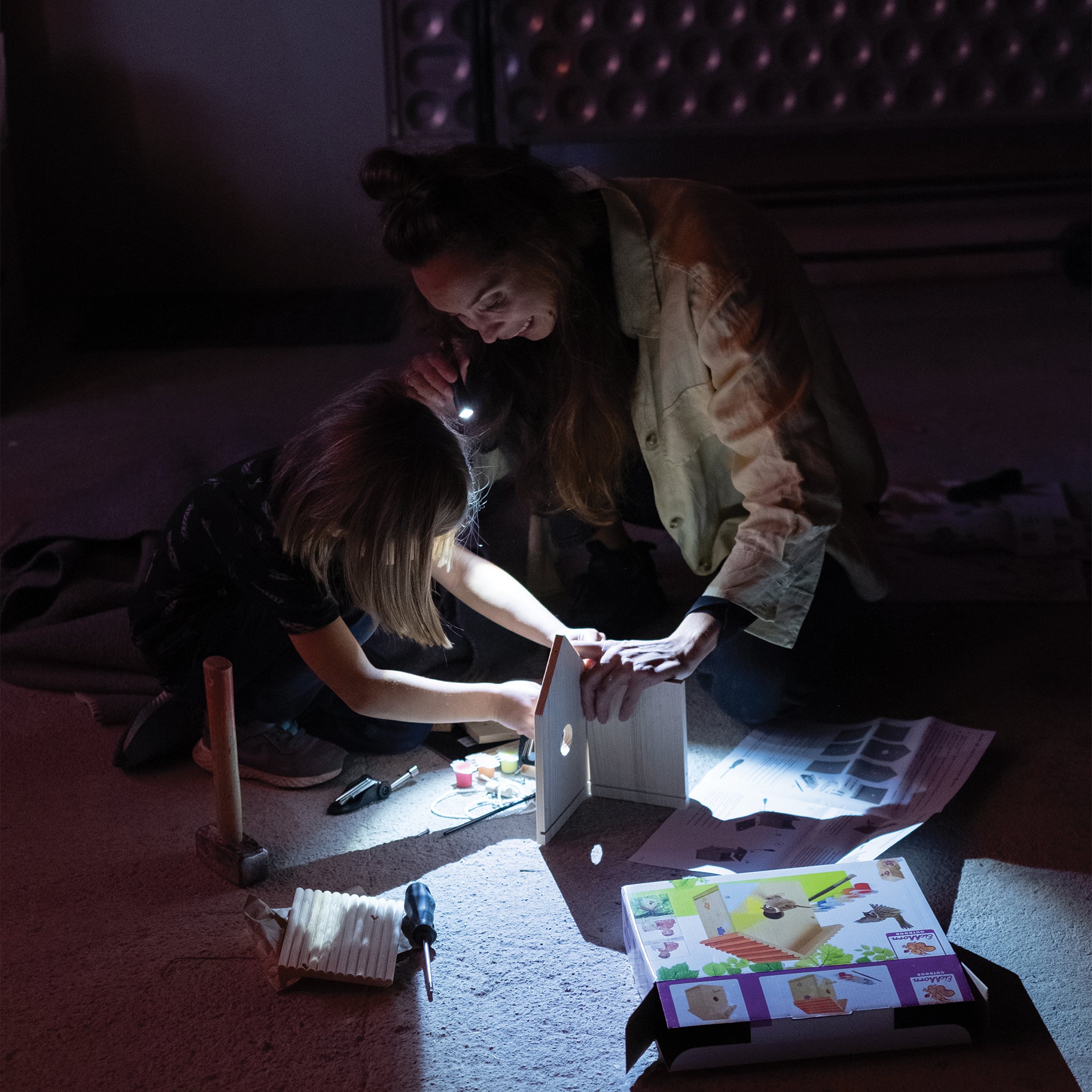 Ledlenser P3 Core Torch held by a person at night illuminating a tabletop project with a child and adult nearby