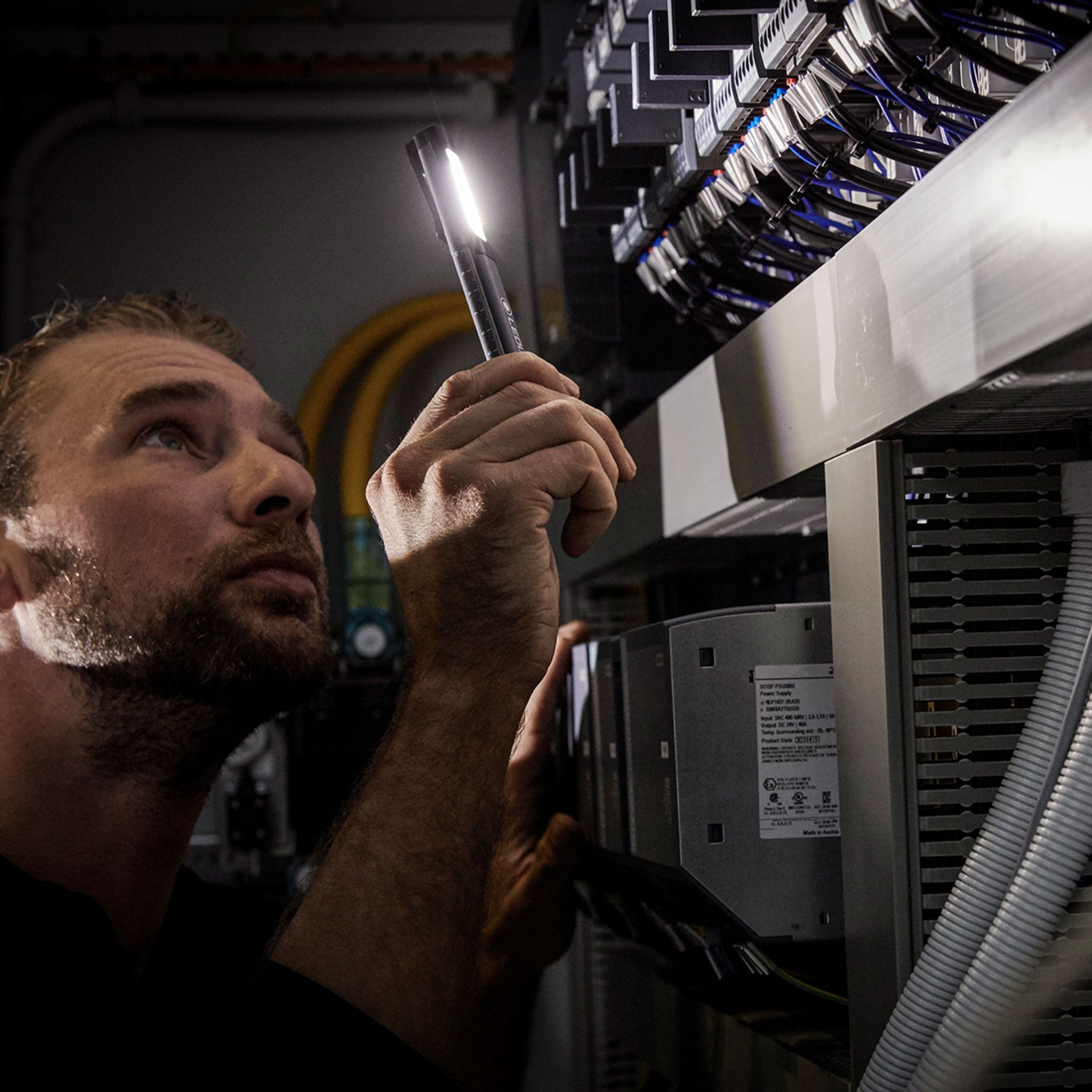 Ledlenser iW2R Work Light being held by a technician inspecting electrical equipment in a server room