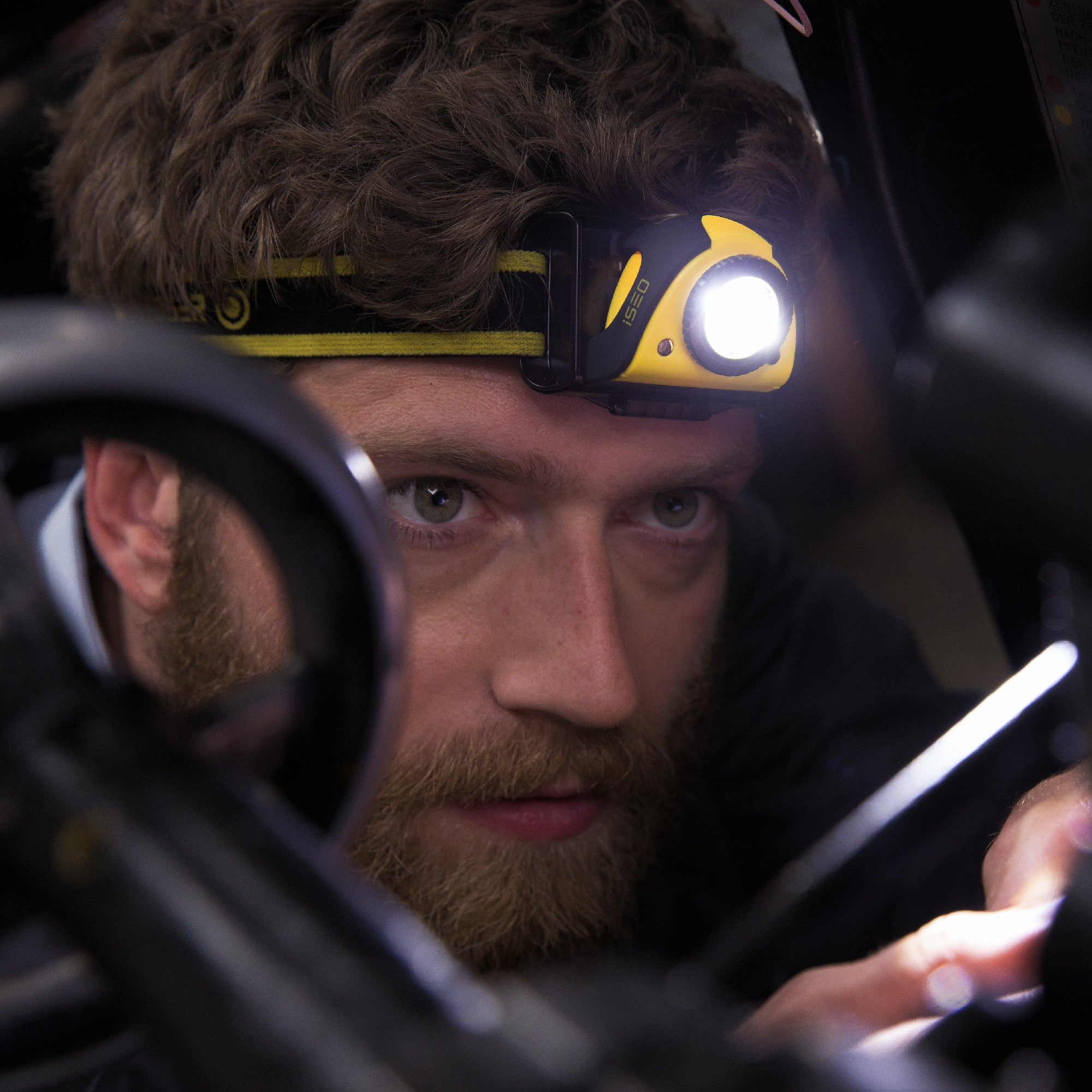 Ledlenser iSEO3 Battery Operated Headlamp worn on a head strap yellow and black LED light turned on