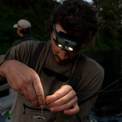 HF8R Core RGB Camo headlamp worn on the head by a person in a dim outdoor fishing setting with dual LEDs visible