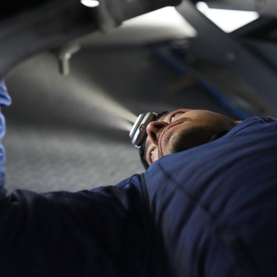 Ledlenser HF4R Work Headlamp worn by a worker in a blue shirt lying on his back with the headlamp illuminating ahead