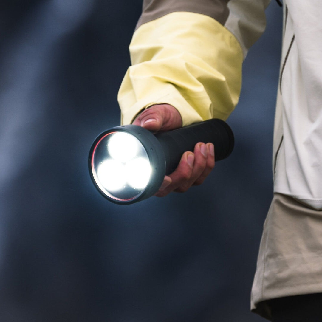 P18R Signature Torch held in a hand showcasing a black cylindrical body and a three LED front with a beige jacket sleeve visible