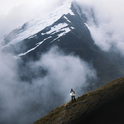 P18R Signature Torch held by a hiker on a foggy mountain slope with a bright LED beam