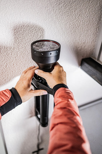 P21R Torch held by hands a black rechargeable flashlight with a large head against a textured wall