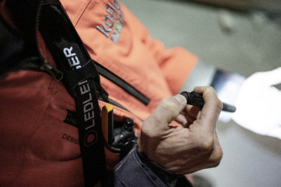 P4R Torch held by a person in an orange jacket; close up of the compact handheld Ledlenser flashlight in use