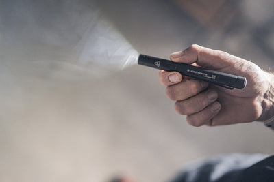 Ledlenser P4 Torch held horizontally in a hand emitting a beam from a compact black flashlight