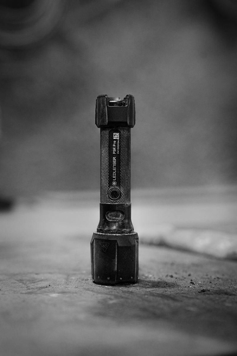 Ledlenser P5R Pro Torch handheld flashlight on a rough surface with a textured grip upright black finish