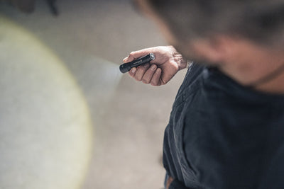 Ledlenser P5 Torch held in a right hand compact flashlight with beam projecting forward in an outdoor setting