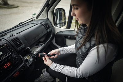 Ledlenser P6R Torch held by a woman seated in a vehicle using the compact rechargeable flashlight inside a car