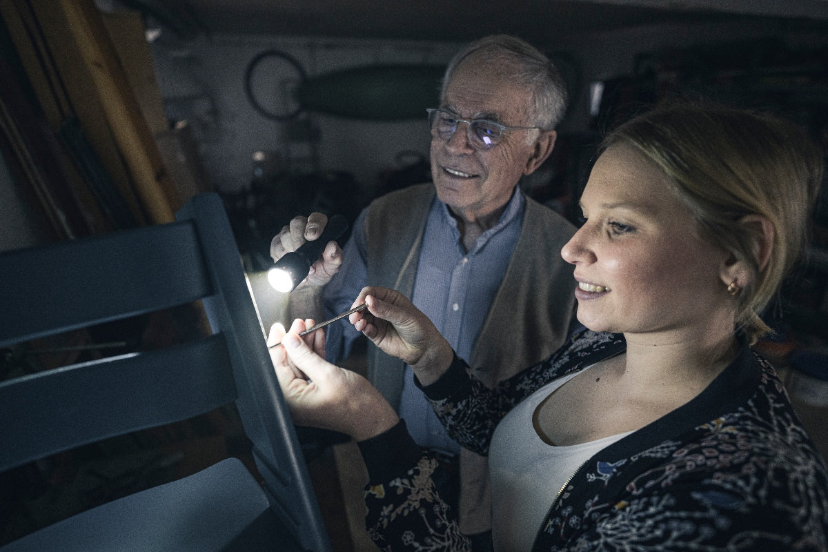 Ledlenser P6R Torch being inspected by a woman and an older man in a workshop handheld flashlight in use