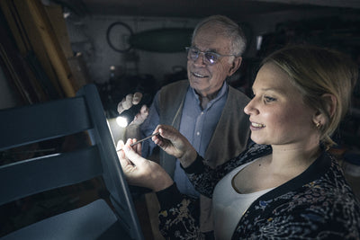 Ledlenser P6R Torch being inspected by a woman and an older man in a workshop handheld flashlight in use
