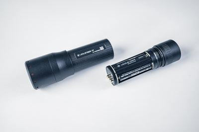 Ledlenser P7 Torch disassembled with battery and end cap visible on a white surface