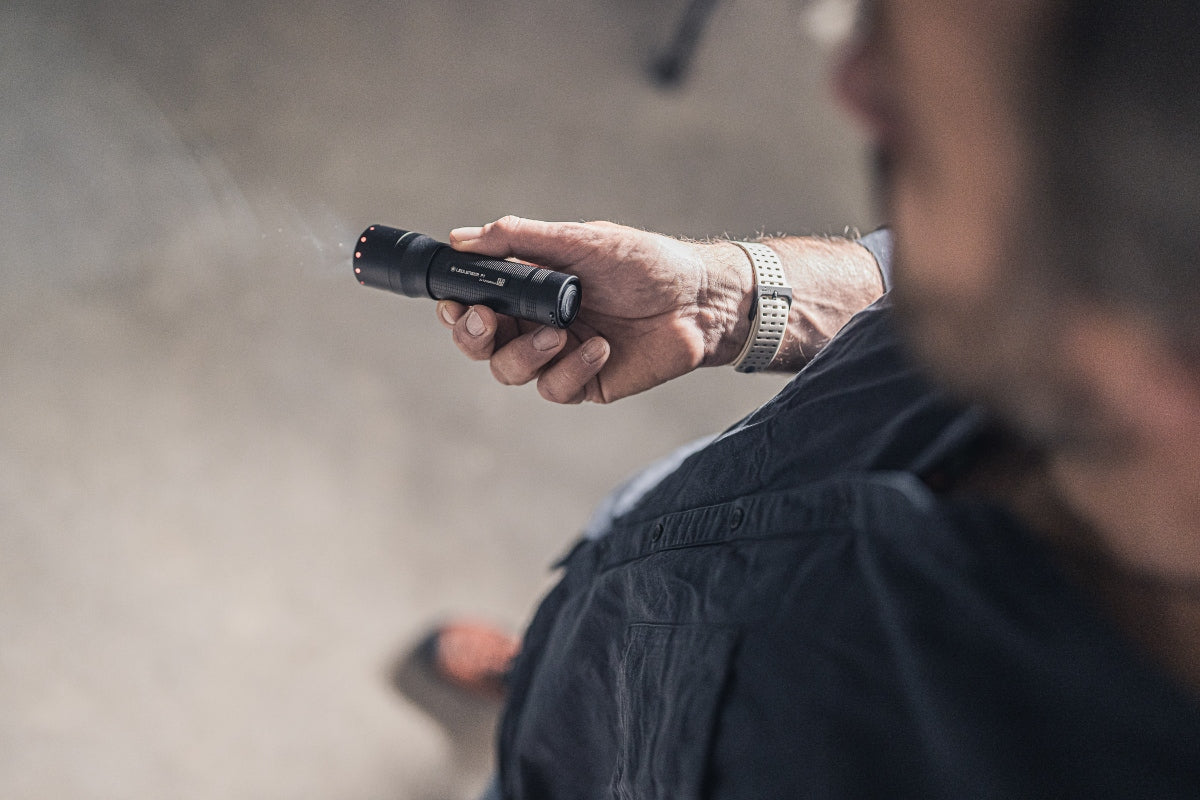 P7 Torch held in a user's hand compact black Ledlenser flashlight with red indicator lights at the tail