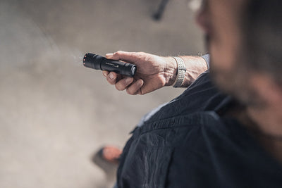 P7 Torch held in a user's hand compact black Ledlenser flashlight with red indicator lights at the tail