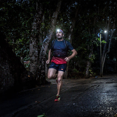 NEO Blue Battery Operated Headlamp worn by a runner at night in a forest with the headlamp on
