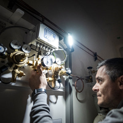 W6R Work Light mounted in industrial panel room man adjusting brass gauge valves as bright LED illuminates work area