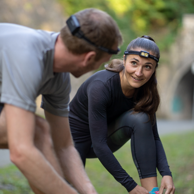 Ledlenser NEO5R Rechargeable Headlamp worn by woman during outdoor activity mounted on a black headband in a park setting
