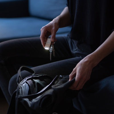 K4R Keychain Light held in a hand over a backpack compact rechargeable USB A torch with a beige silver finish