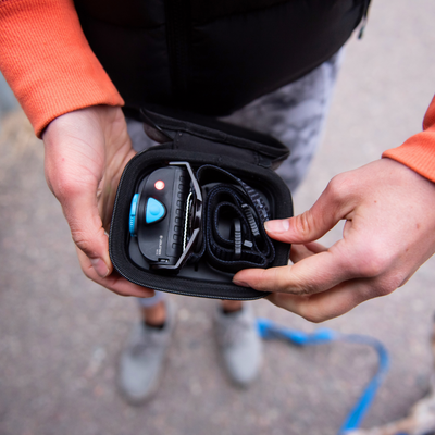 MH5 Powercase Combo headlamp and charging case inside a compact black carry case being opened with a blue control button visible