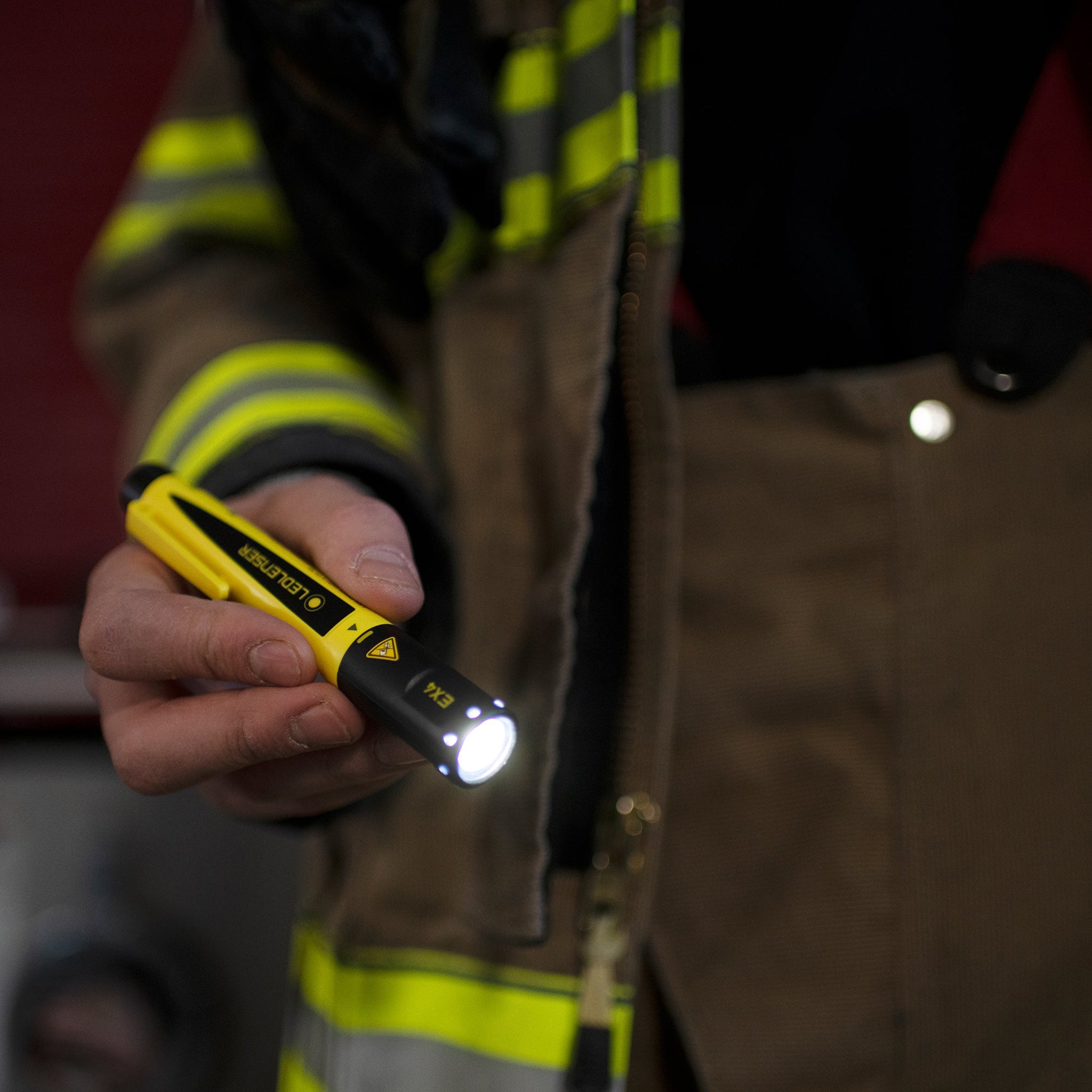 EX4 Torch held in a gloved hand showing its yellow and black body with the front light on