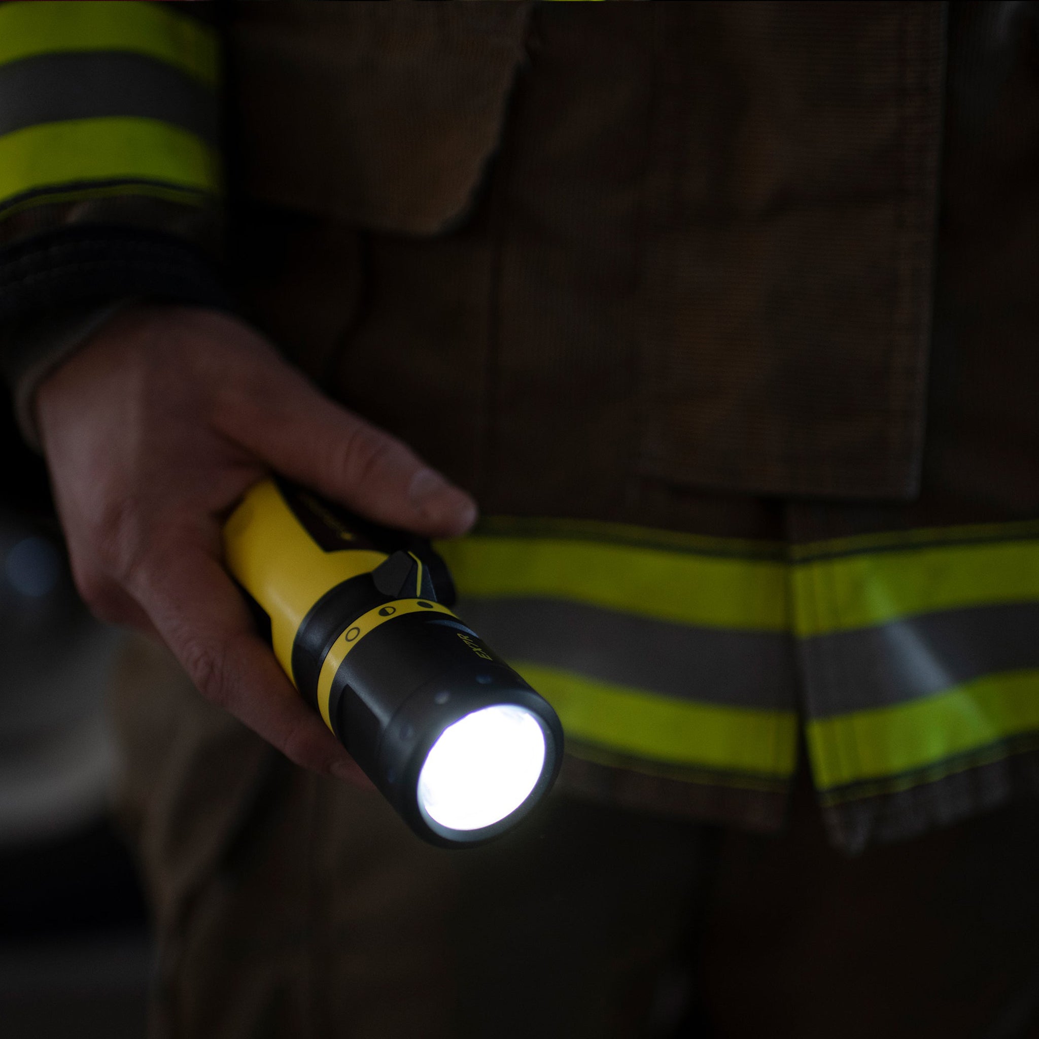 Ledlenser EX7R Torch held by a worker in a high visibility jacket yellow and black body with the light on