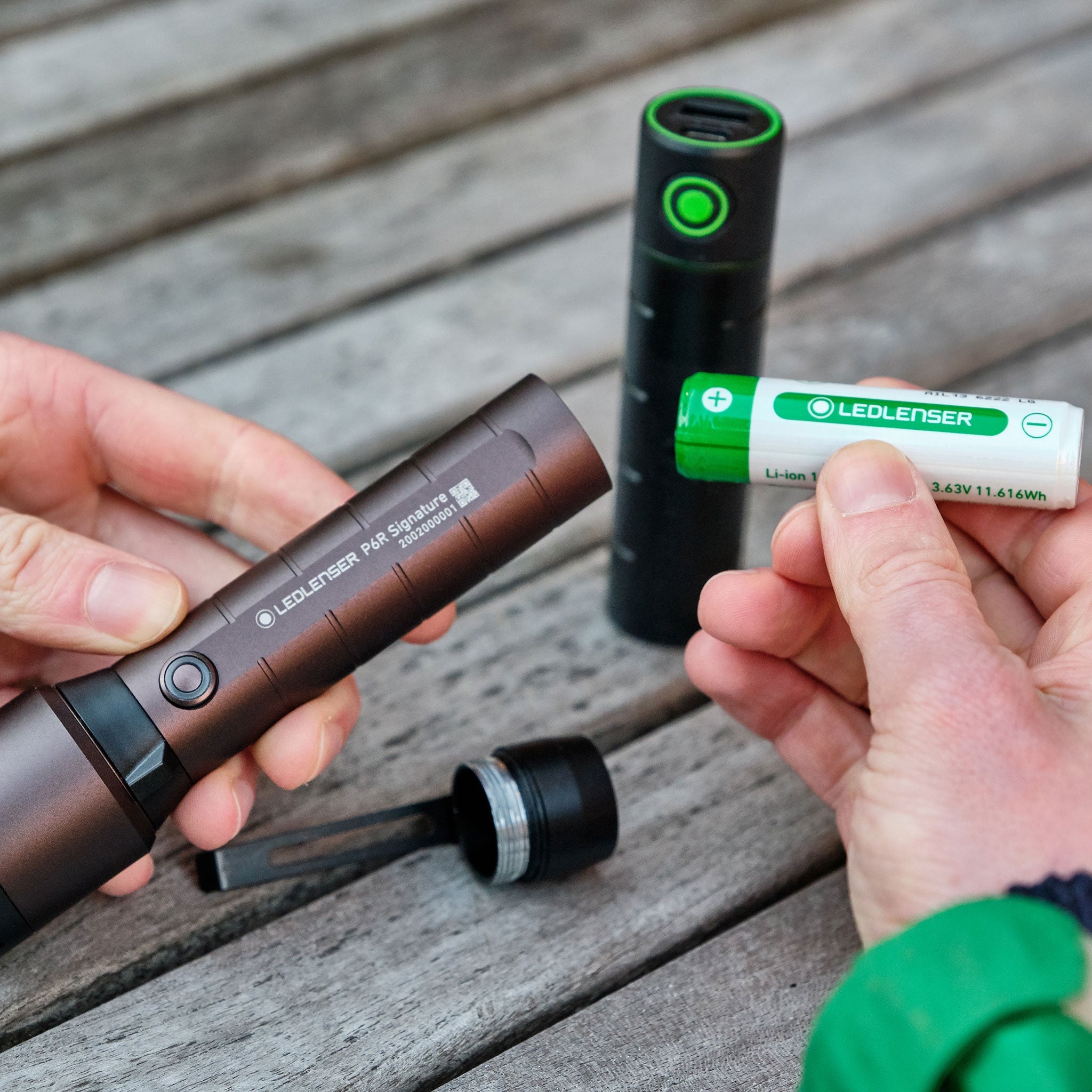 Flex3 Powerbank image showing hands holding a brown Ledlenser P6R Signature torch body and a green Li ion battery being inserted into it