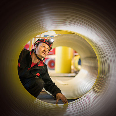 Ledlenser H15R Work Headlamp worn by a worker inside a large metal pipe with headlamp lit