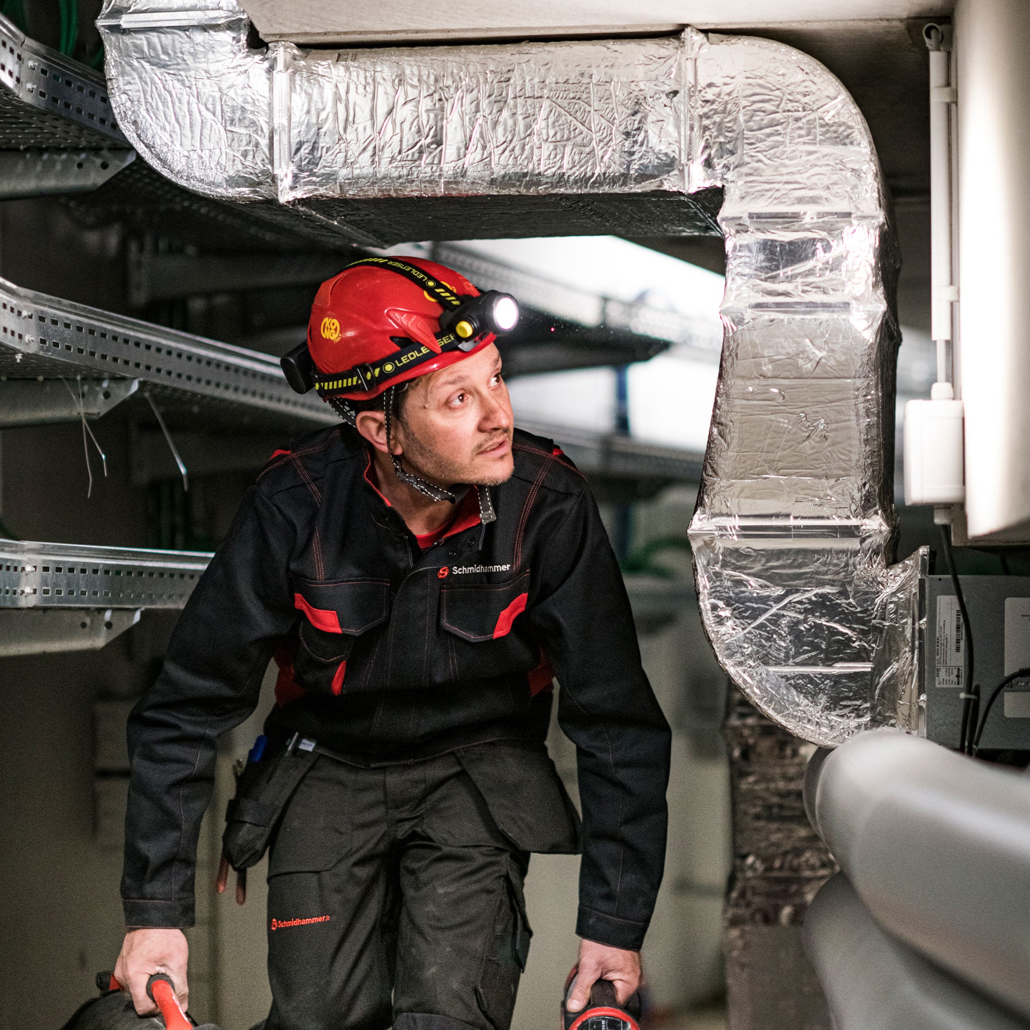 Ledlenser H15R Work Headlamp worn by a worker in an industrial setting with a red helmet and mounted headlamp