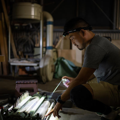 Ledlenser H5R Core Headlamp worn by man in a workshop kneeling beside equipment with the headlamp on