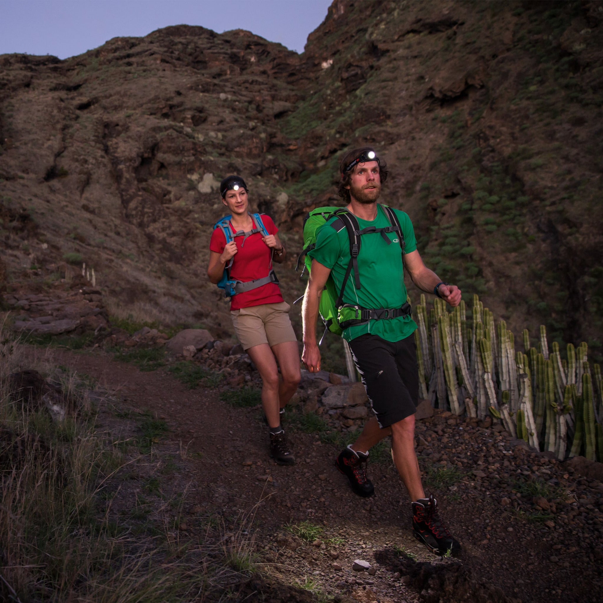 Ledlenser H7 2 Headlamp worn by a man on a rocky trail at dusk with a woman behind him both wearing headlamps