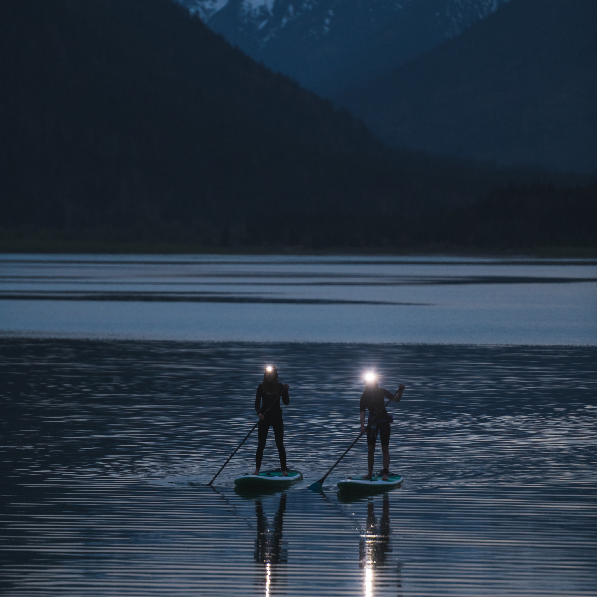 Ledlenser H7R Signature Headlamp worn by two paddlers on a lake at dusk with their headlamps illuminated