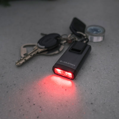 Ledlenser K6R Keychain Light compact black USB rechargeable flashlight with a key ring and red illumination on a grey surface