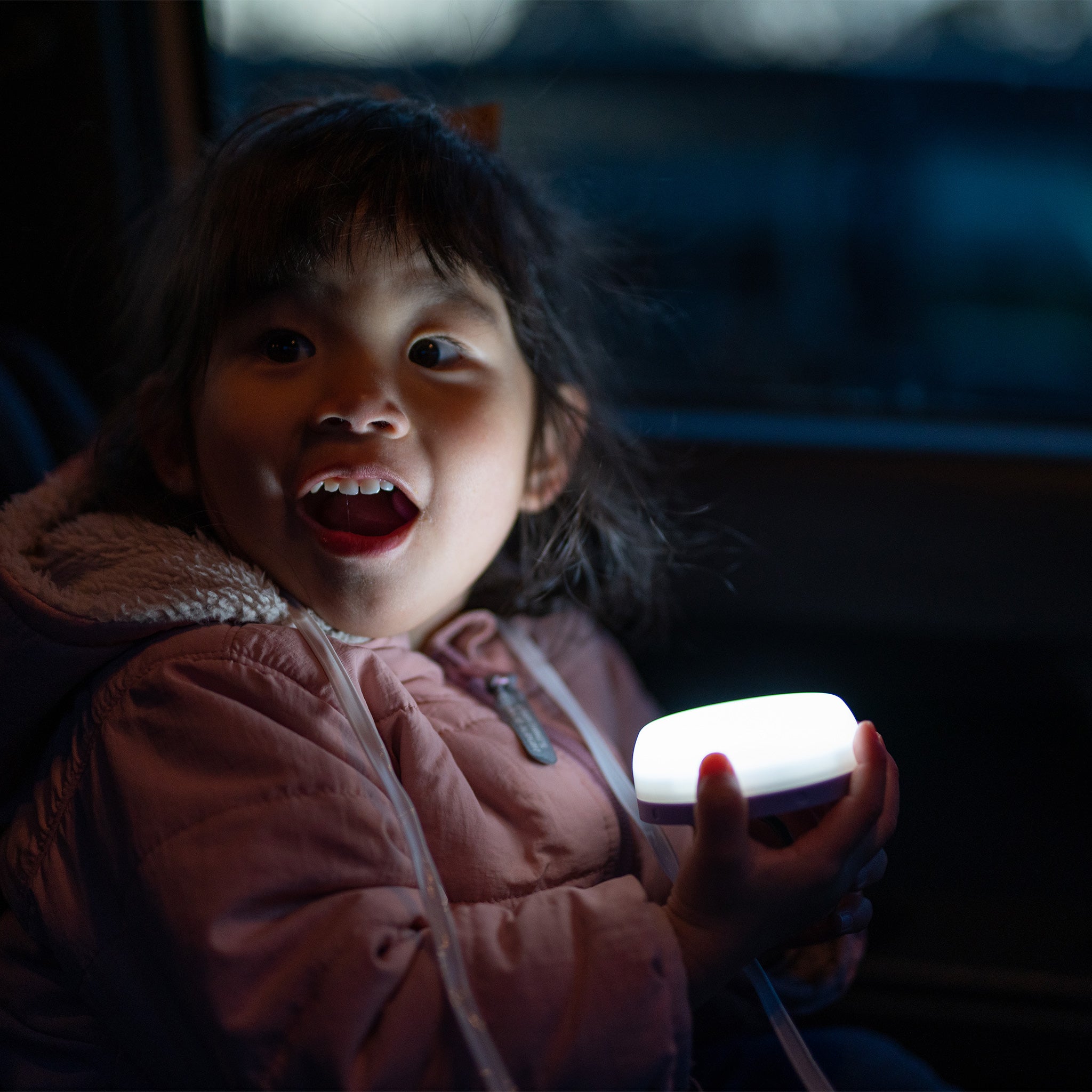 Ledlenser Kidcamp6 Lantern held by a child in a dark vehicle the lantern glowing softly in their hands