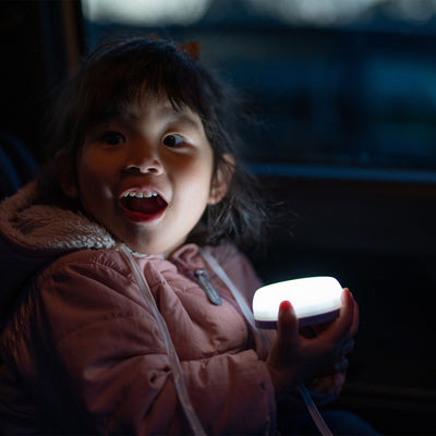 Ledlenser Kidcamp6 Lantern held by a child in a dark vehicle the lantern glowing softly in their hands