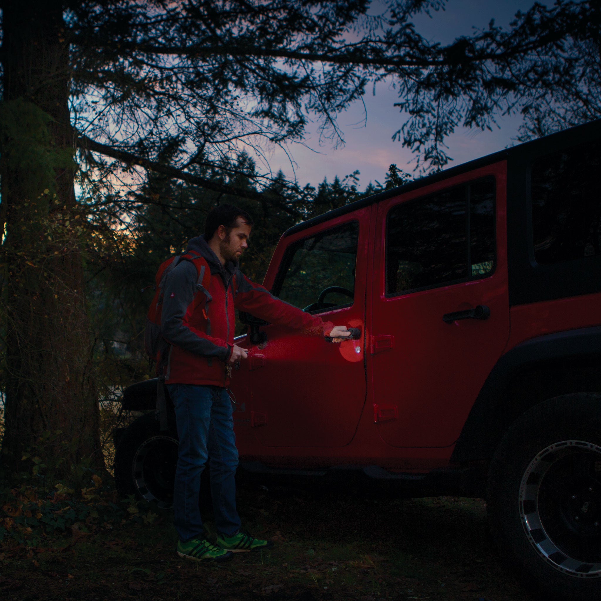 P2 Battery Operated Torch held by a man in a red jacket beside a red SUV at dusk lighting the door handle