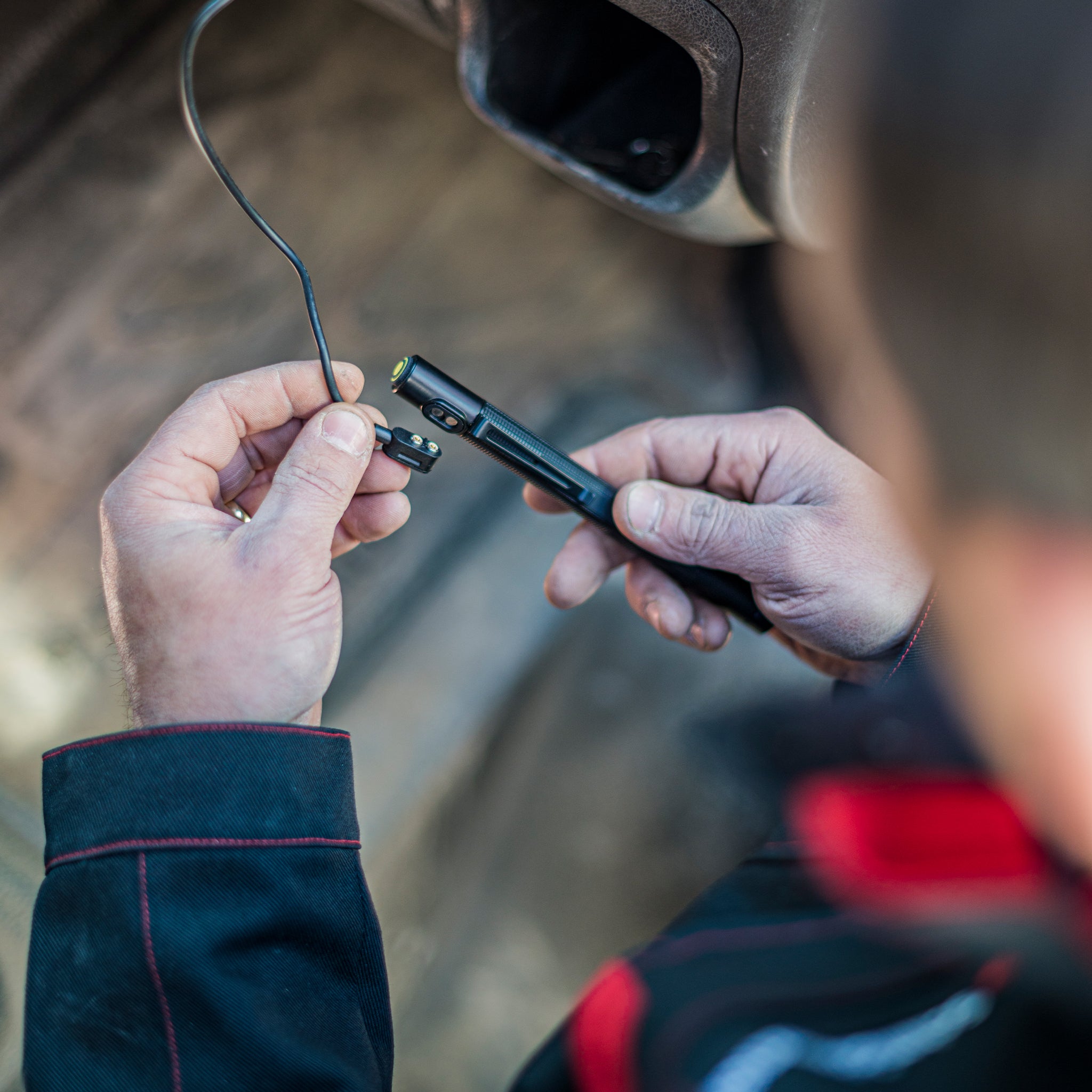Ledlenser P4R Work Torch being charged close up of a black compact handheld torch with a yellow accent connected to a charging cable